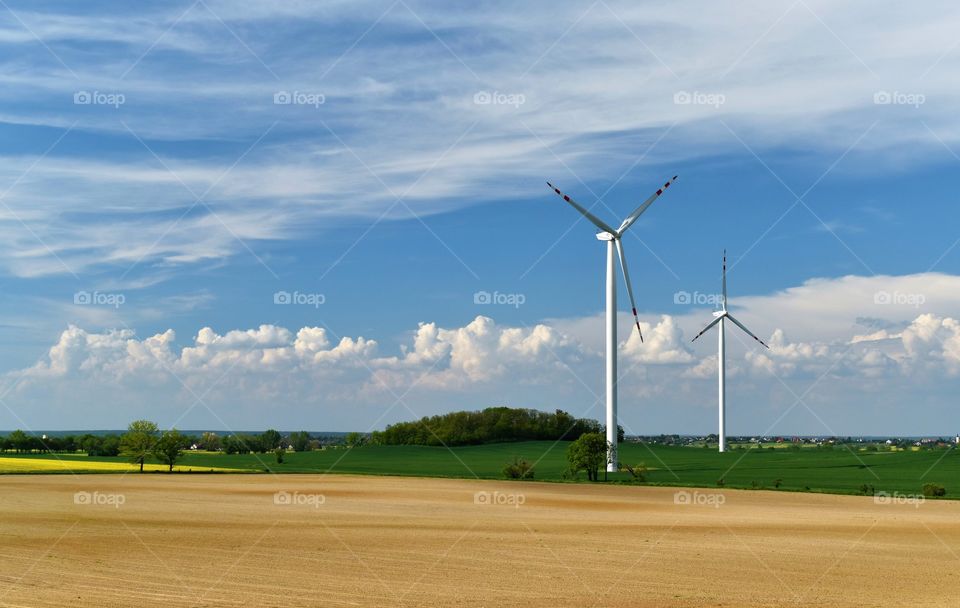 Wind power plant on the field on a background of blue sky and white clouds