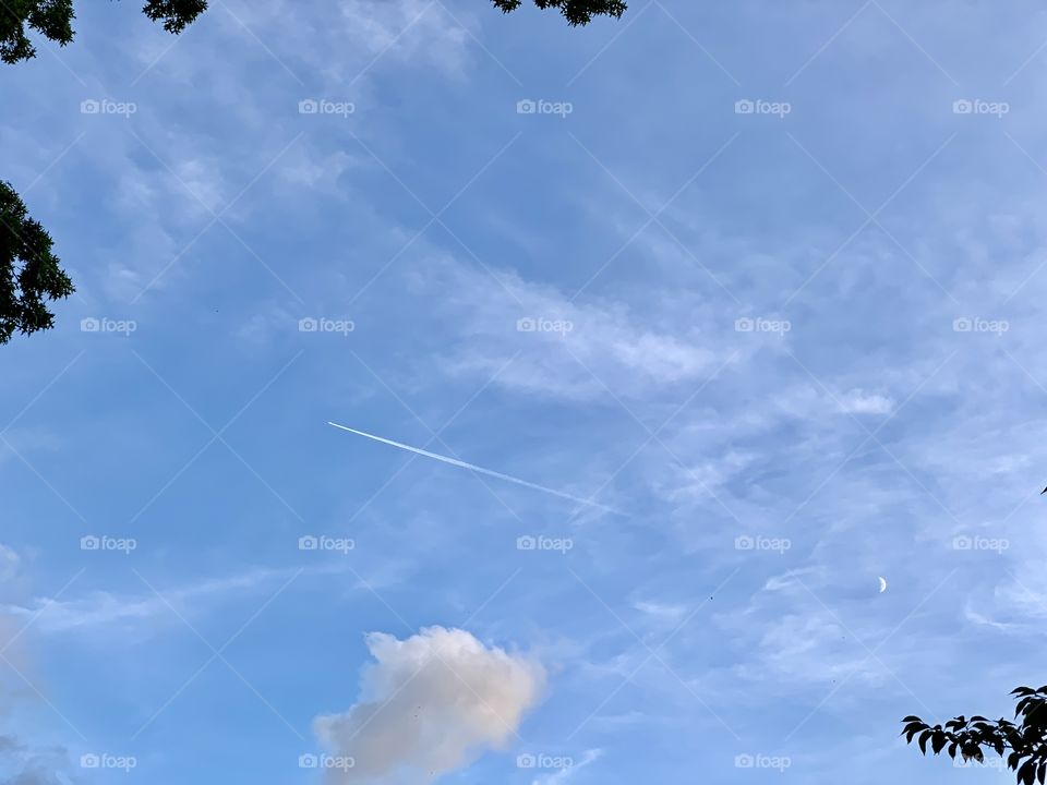 Jet plane, white trail, half moon in an open space in the skies. Nature’s beauty. 