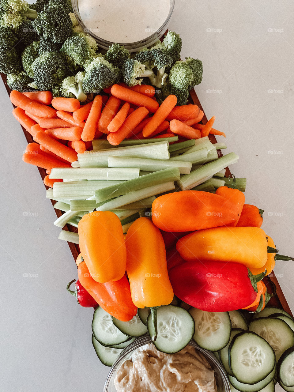 Colorful vegetable board with peppers, cucumbers, celery, carrots and broccoli on a charcuterie board.