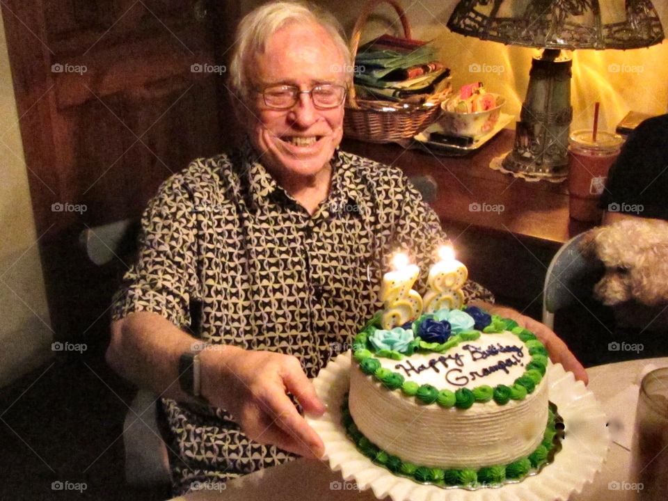 Older man holding birthday cake with numbers reversed as joke. Big smile with birthday cake.