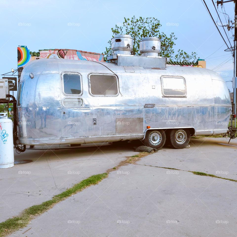 Pastel blue sky hues reflected on a silver retro travel camper.