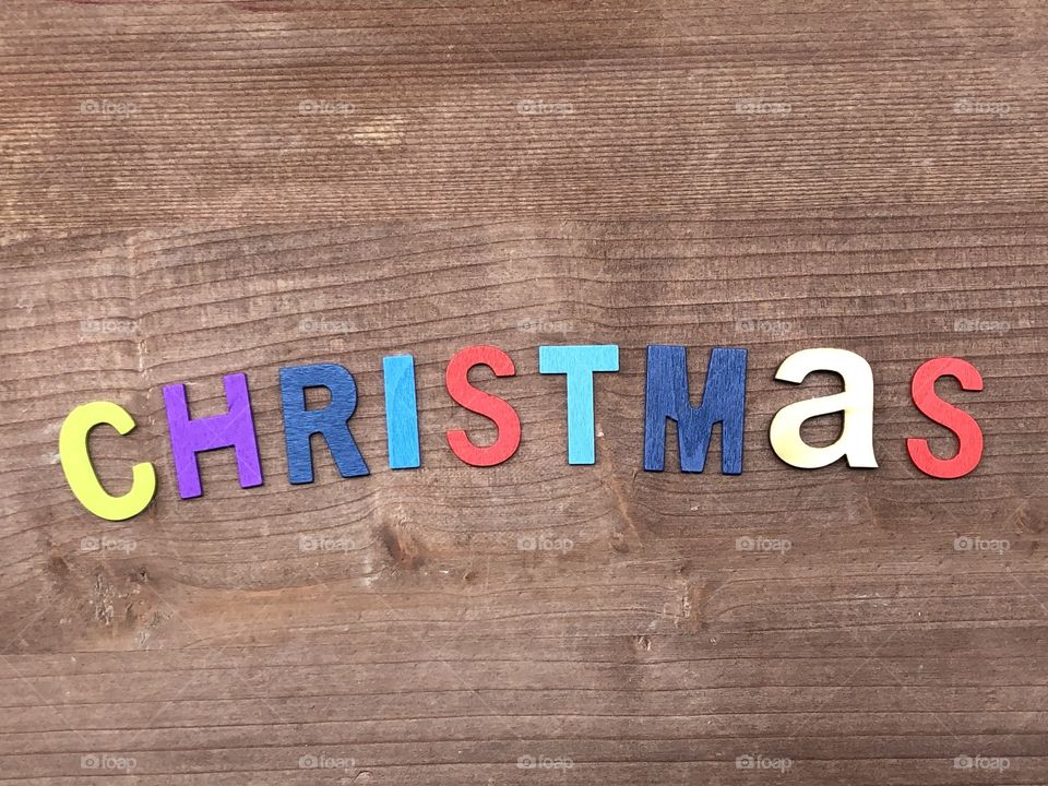 Christmas word composed with colored wooden letters over woodem board