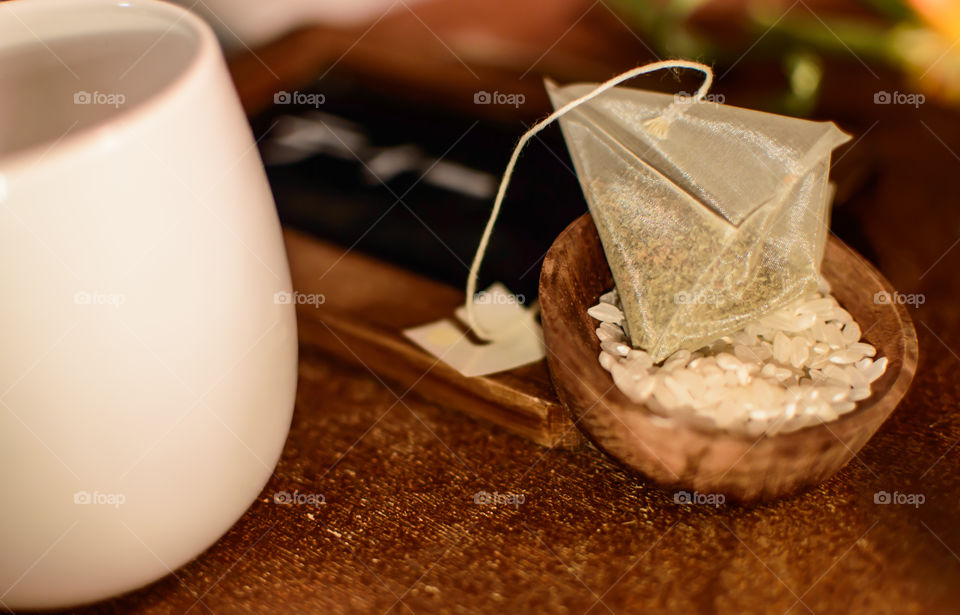 Japanese green tea with toasted rice in triangle fine material tea bag in bowl with rice and tea cup on wooden table conceptual healthy lifestyle zen background 