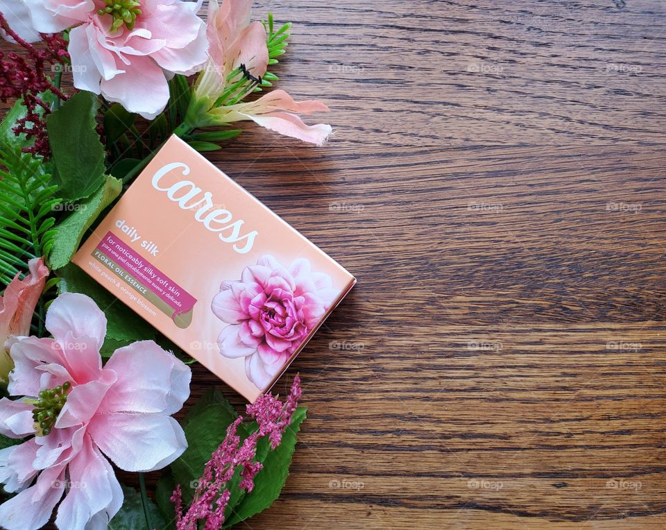 The new look single pack Caress bar on the left accented by matching florals on a wood surface.