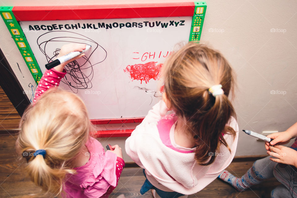 Children drawing a pictures learning a letters playing together using whiteboard and markers