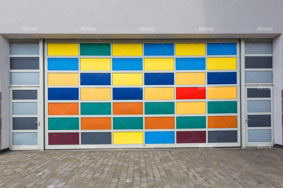 Rectangle, broad garage door covered with rectangles in many bright different colors 