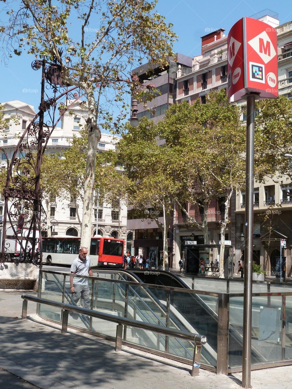 a man enters a subway entrance in the center of the city, in the background a bus.