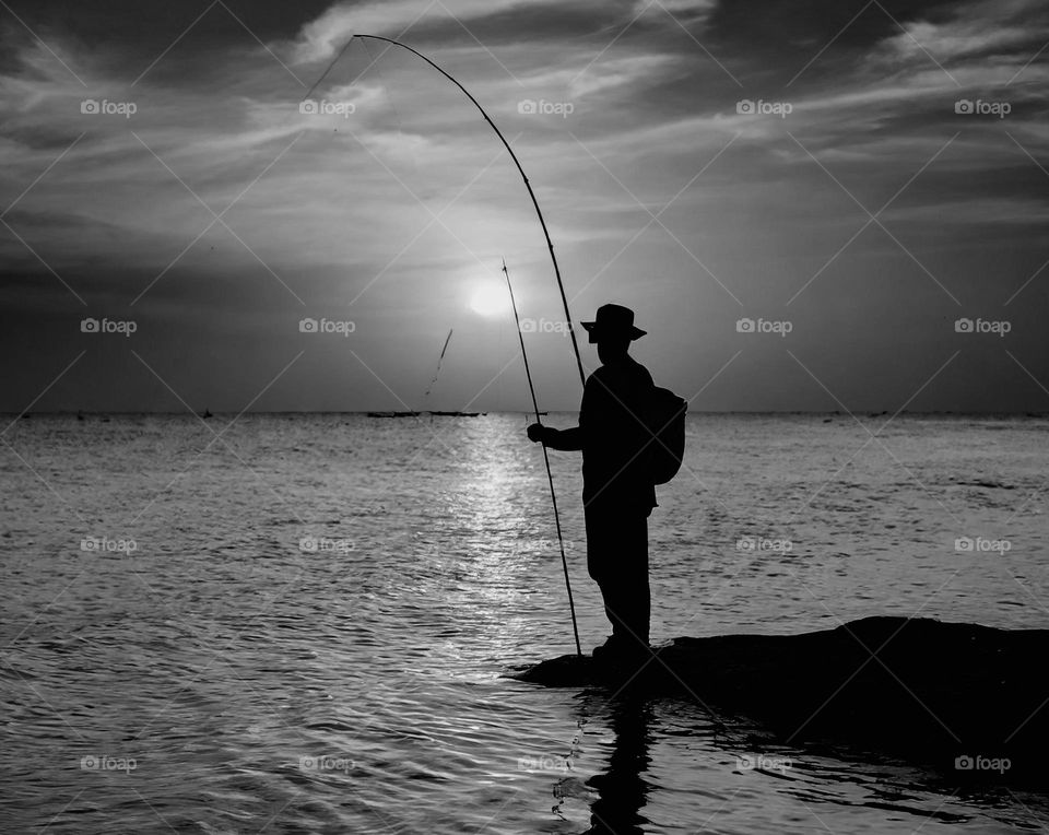 A black and white photograph of a man leisure fishing 