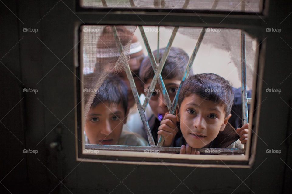 Boys peeping curiously into a window in a town called Peshawar, Pakistan.