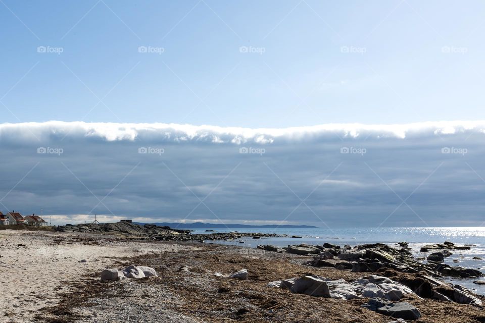 Bad weather changes and blue sky is coming, broad thick cloud front moves away over the ocean 