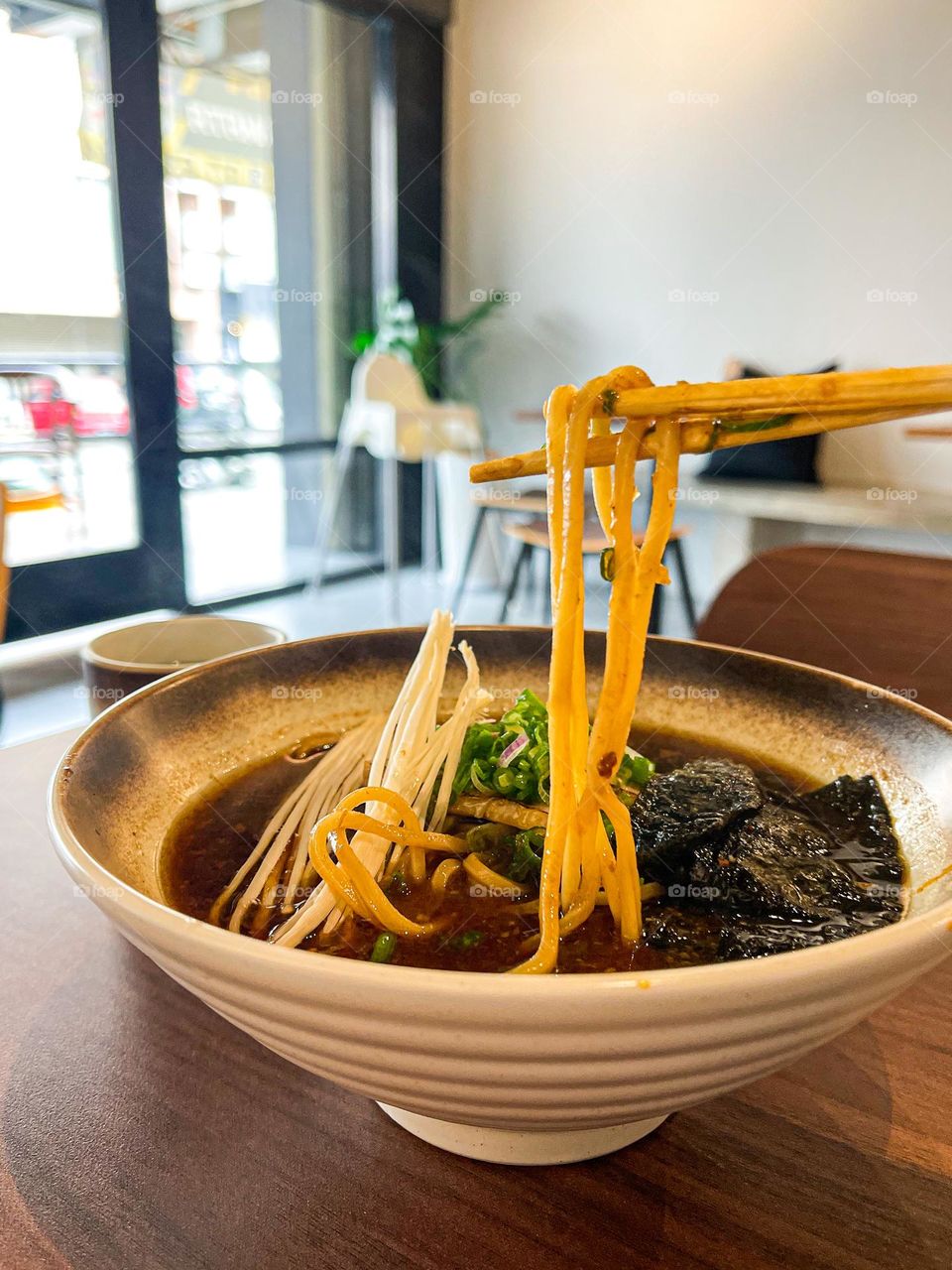 Japanese black soup ramen in close up view and using chopsticks to hold the noodles 