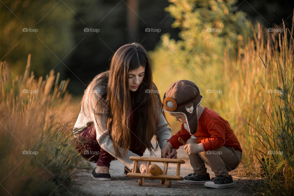 Mother and son with wooden plane at sunset