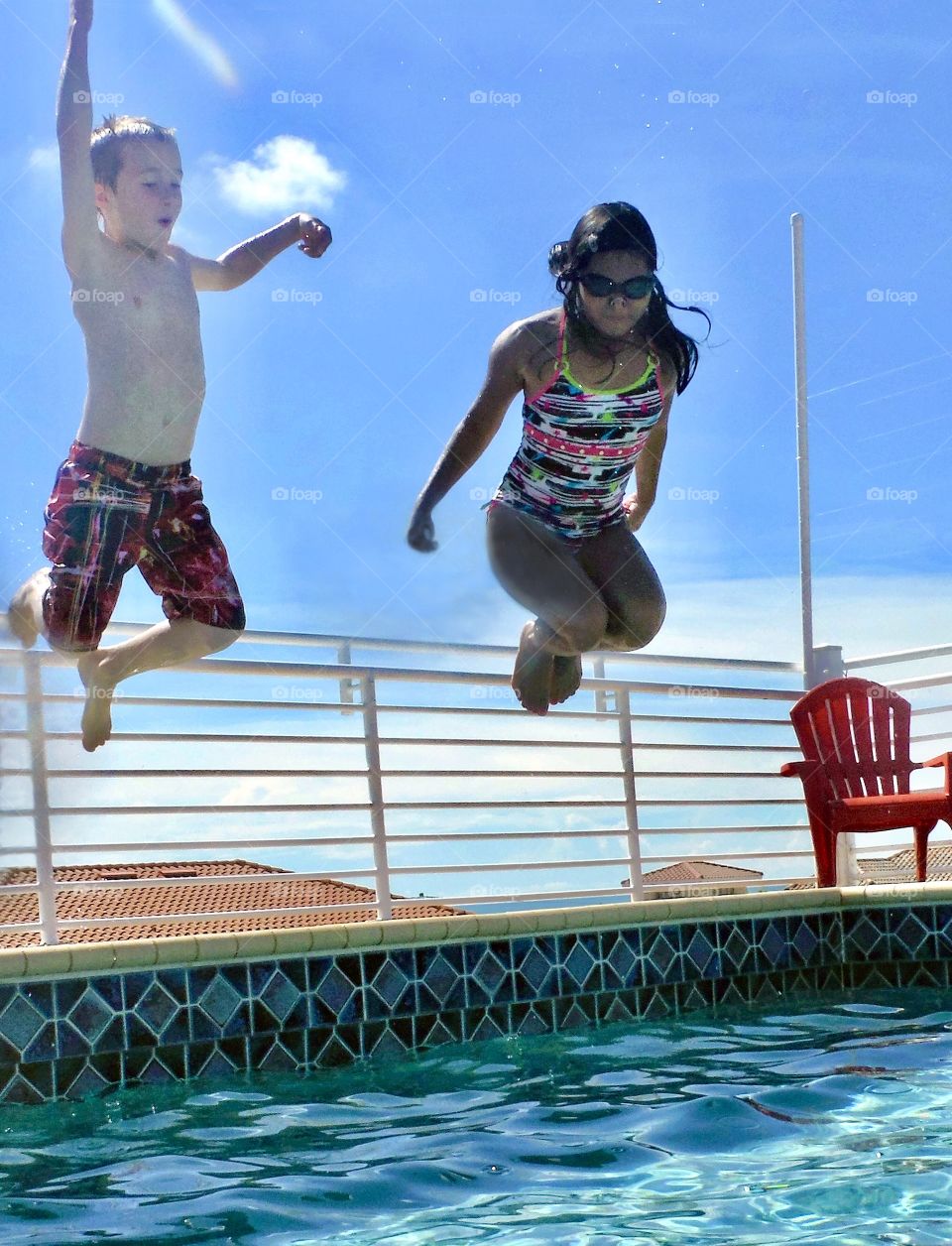 Summer vacation, brother and sister jumping into a pool