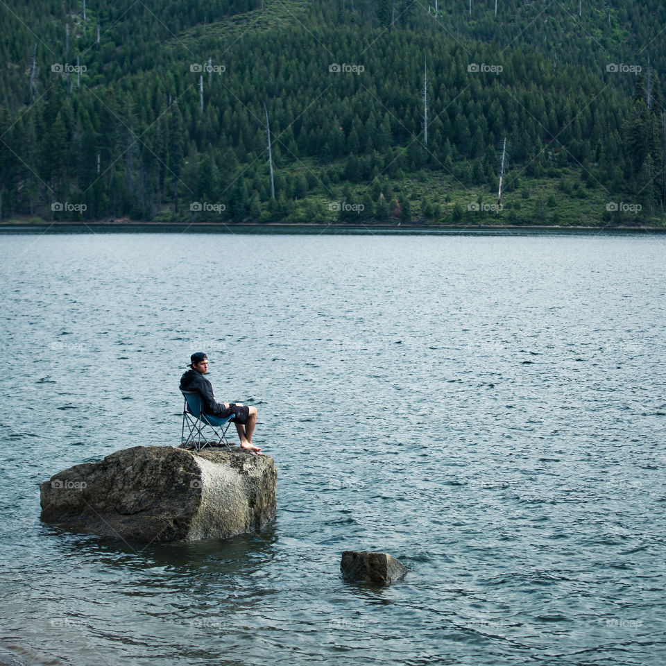 Man sitting on chair near river