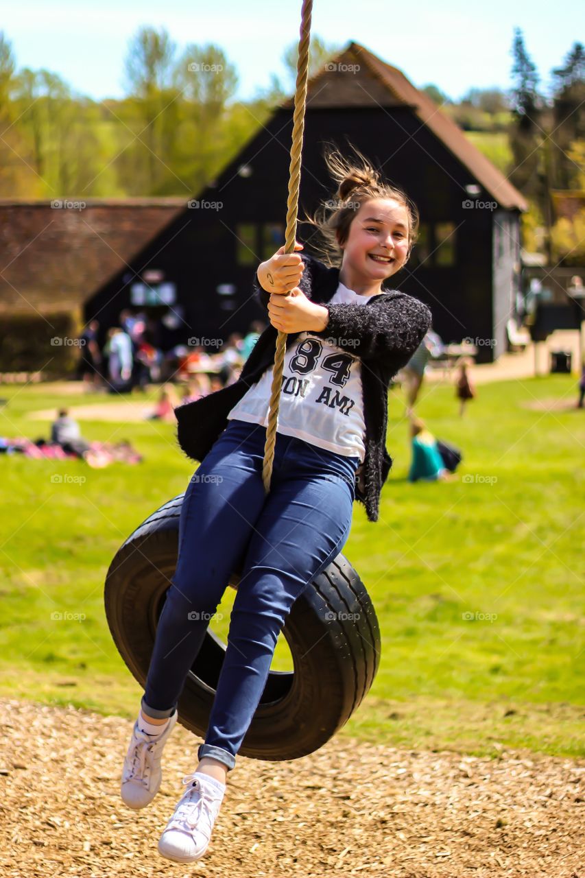 Happy girl playing in park sitting on wheel