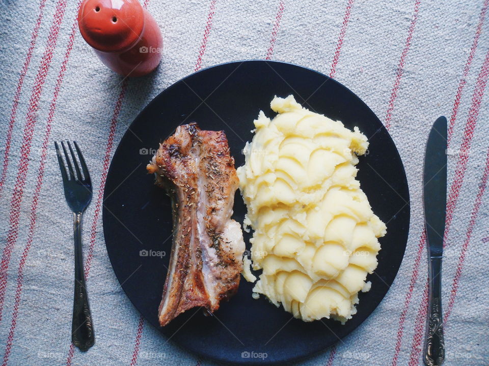 grilled pork ribs, potato puree on a black plate