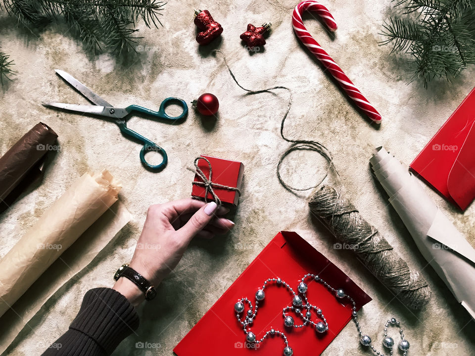 Female hand wrapping handmade Christmas gifts on rustic grunge background 