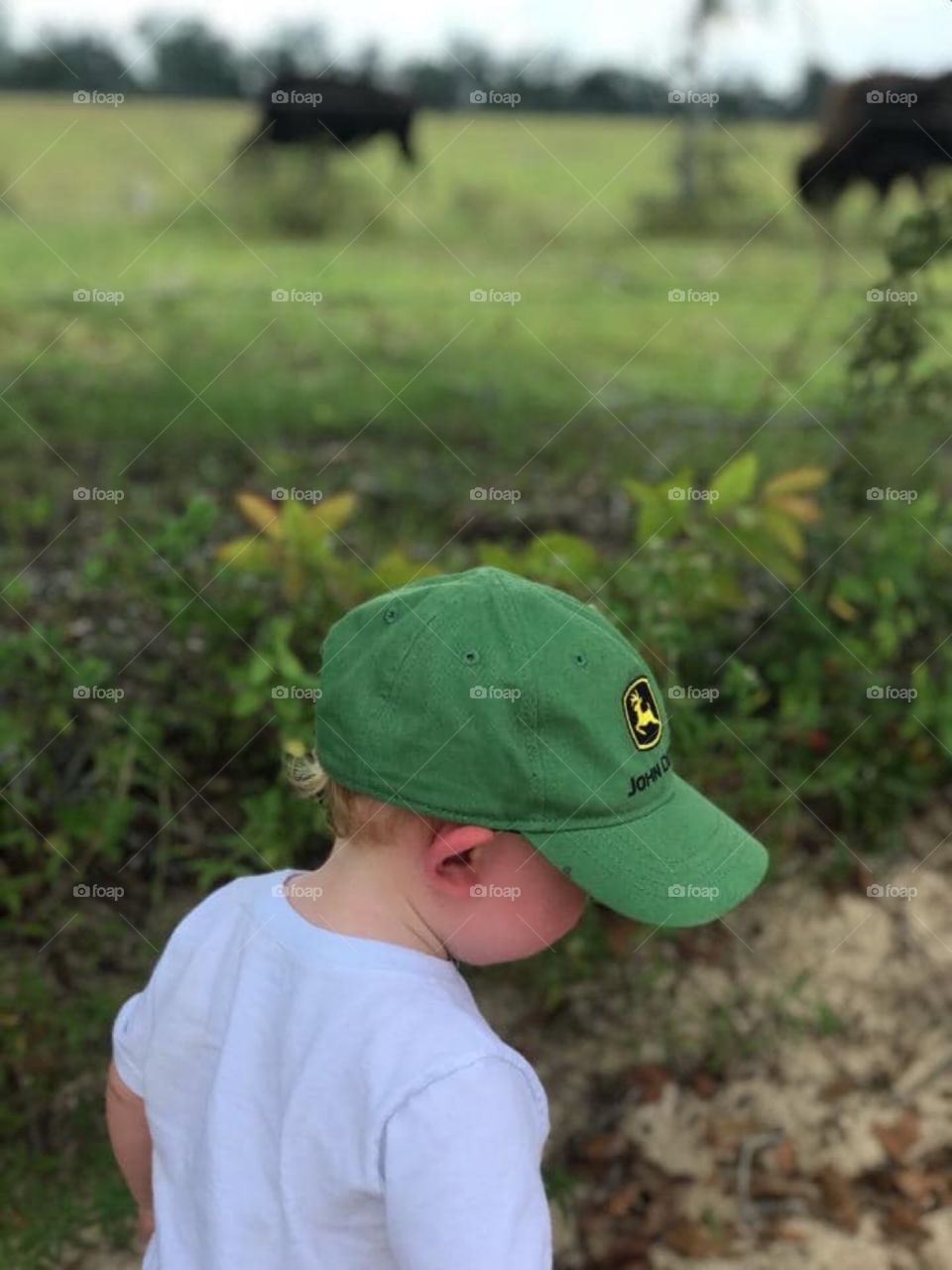 Toddler wearing john deer hat playing outside 