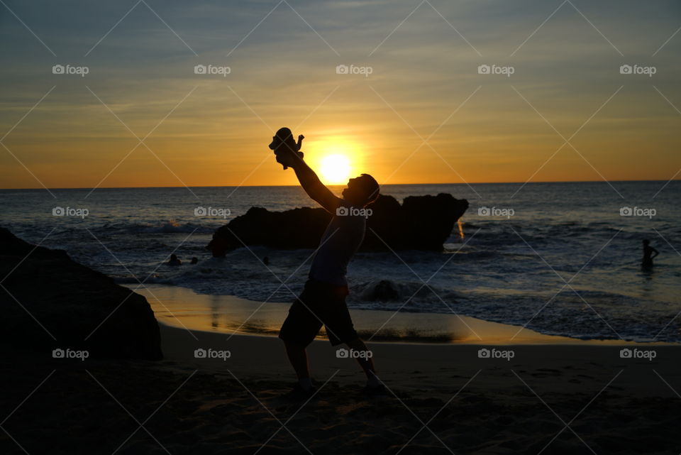 Beautiful Hawaiian sunset in background and stunning shadow figures of father and daughter in foreground 