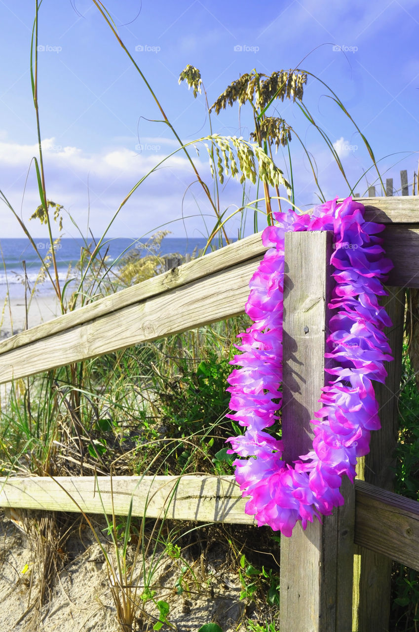Beach concept. Lei hanging on a beach fence. 
