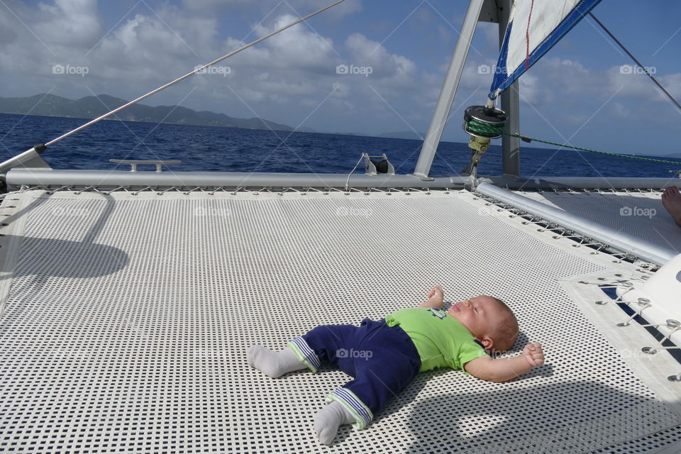 Baby sleeping on the net of a catamaran