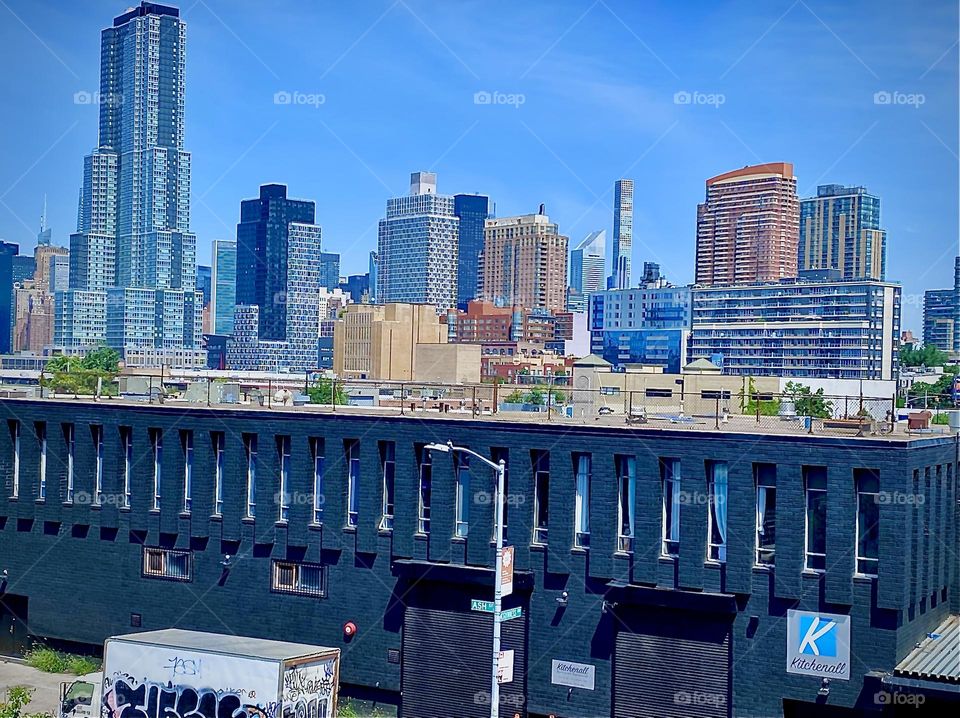 „Long Island City“, Queens, NY can be seen from here standing on the staircase going up to the top of the „Pulaski Bridge“ from the „Greenpoint“, Bklyn side on a bright but very hot sweltering summer day in 2022. Hypnotic Productions