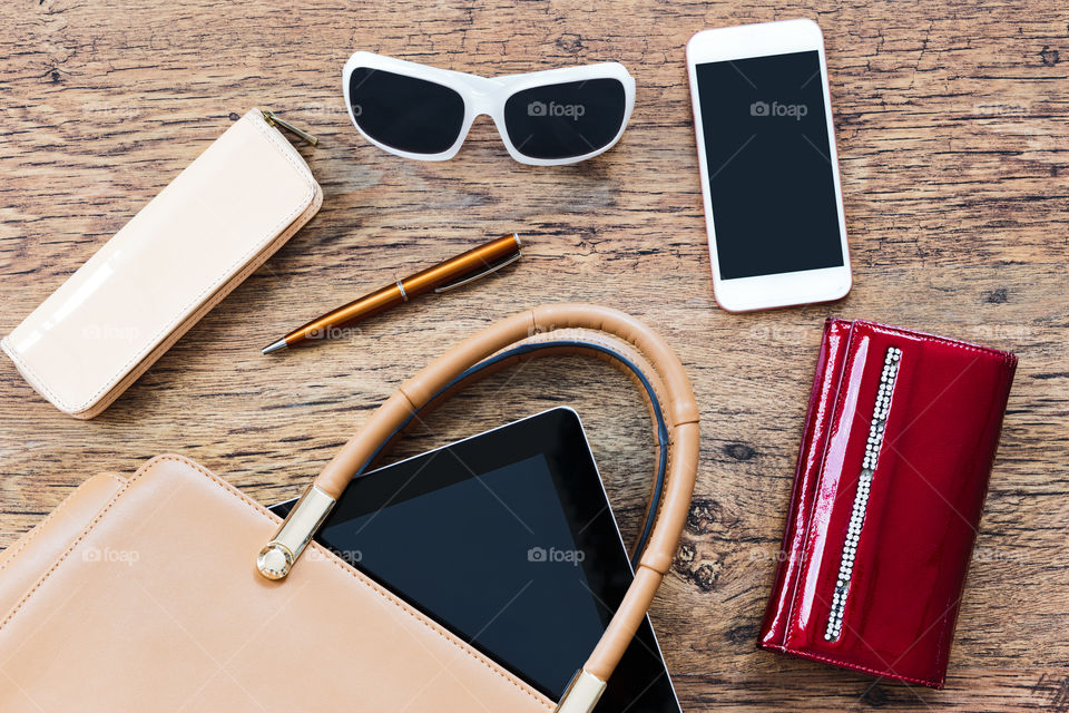 Smartphone sunglasses wallet and other things pulled out of handbag put on a table