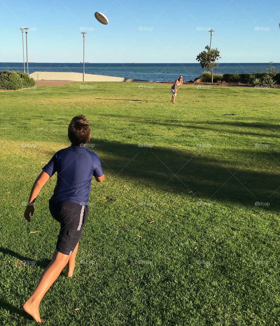 Mother and son playing frisbee, family vacation at the ocean 