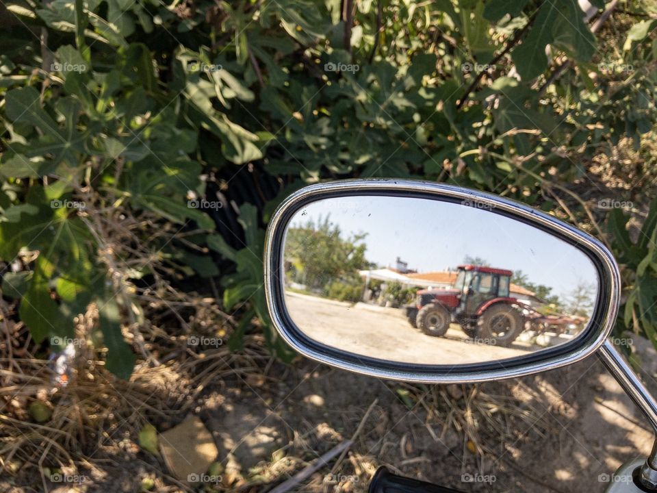 Red tractor in motorcycle mirror