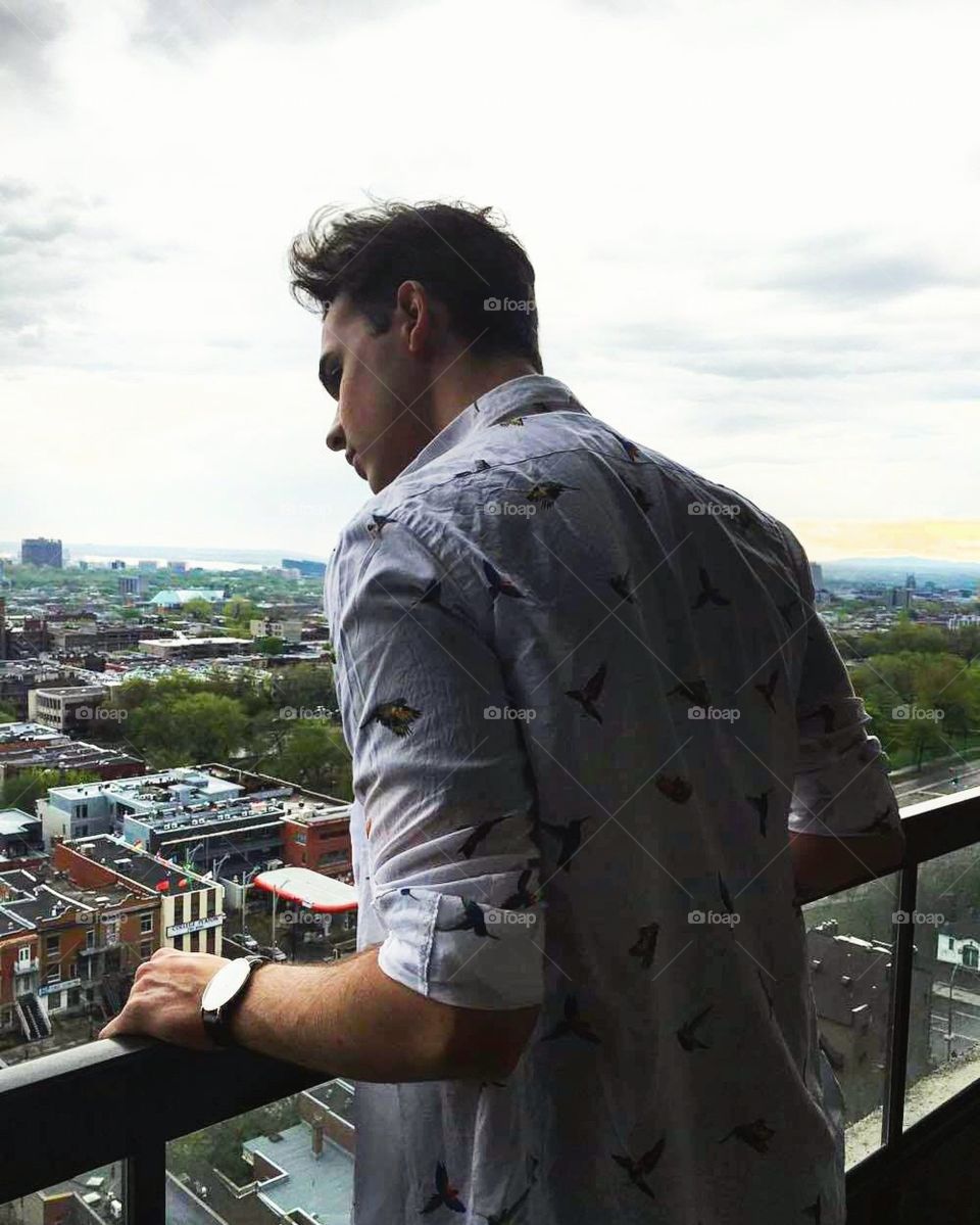 Boy looking over the city of Montreal, Canada wearing a bird print shirt 