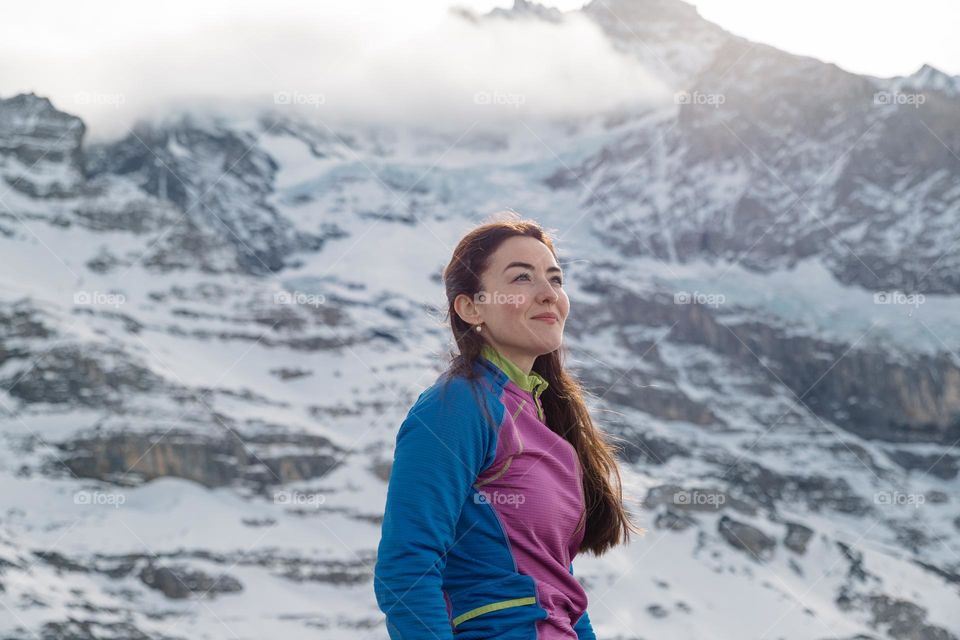 Portrait of a beautiful young woman, admiring the mountains around here, while on a hike in the Swiss Alps.