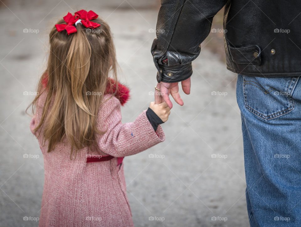 Daddy holding girls hand. A dad and young daughter holding hands walking away from the camera