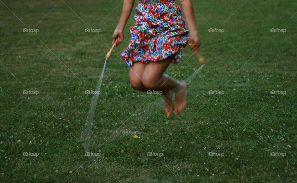 Low section of a woman jumping on a rope on the grass