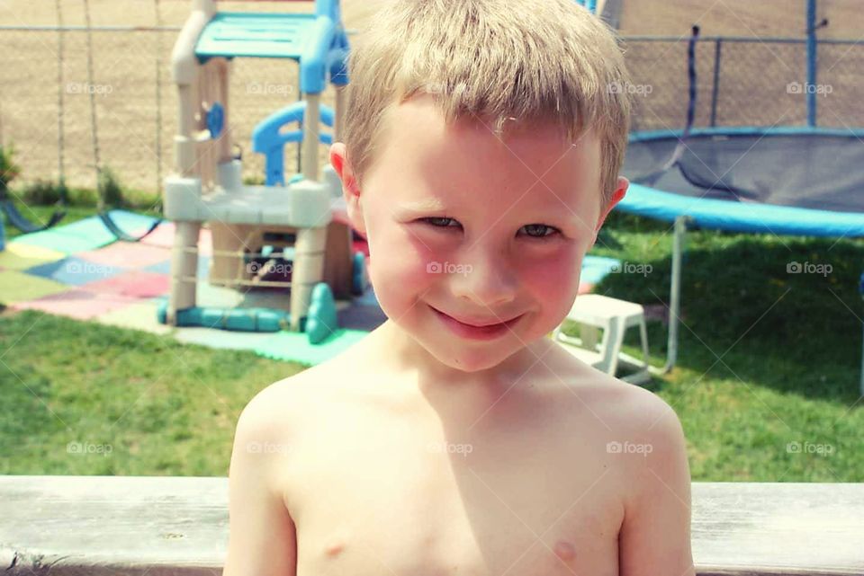 A child stares into the camera, almost hauntingly, with play equipment in the background.