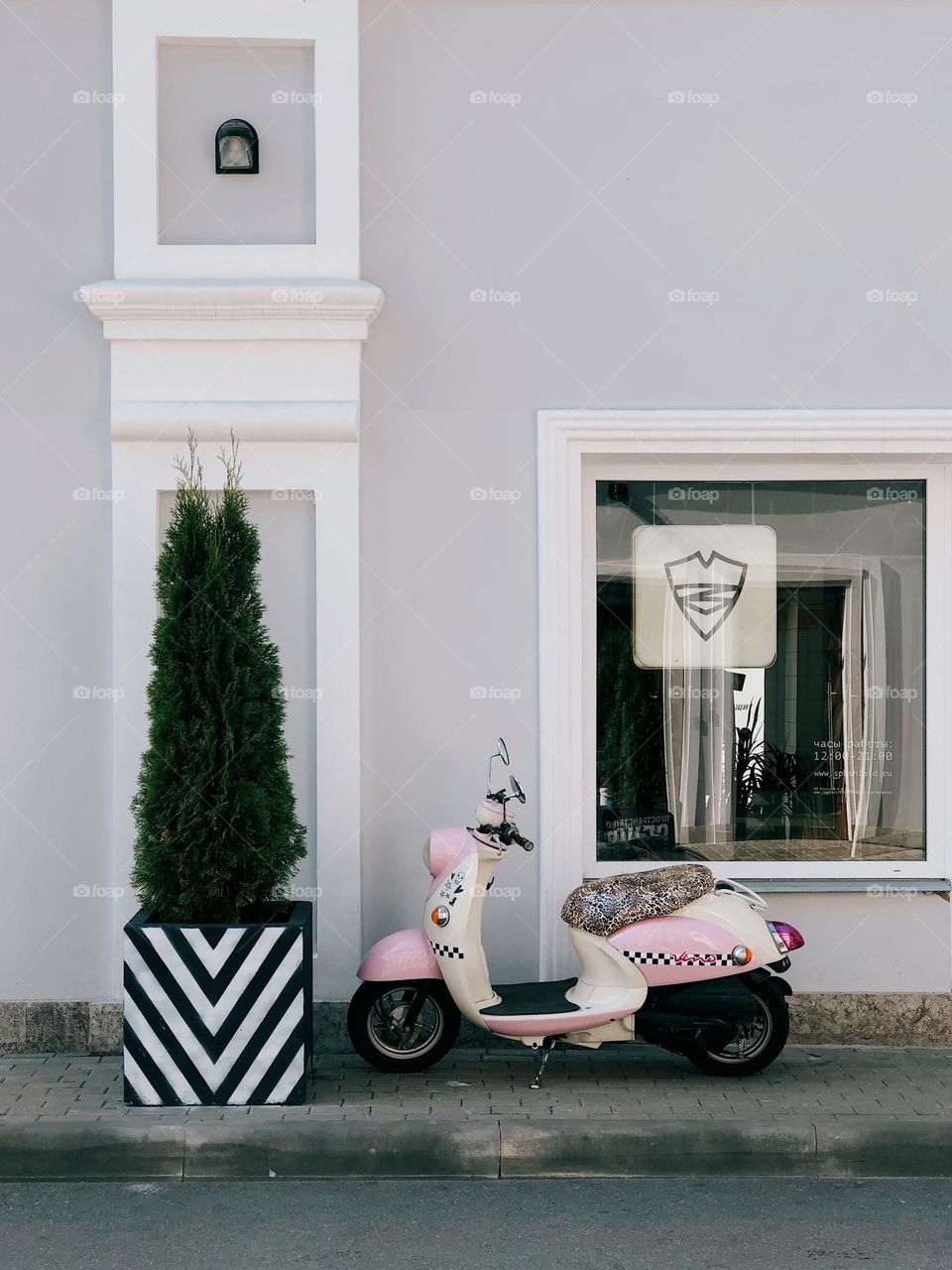 Lonely pink scooter standing near grey wall on the street, nobody 