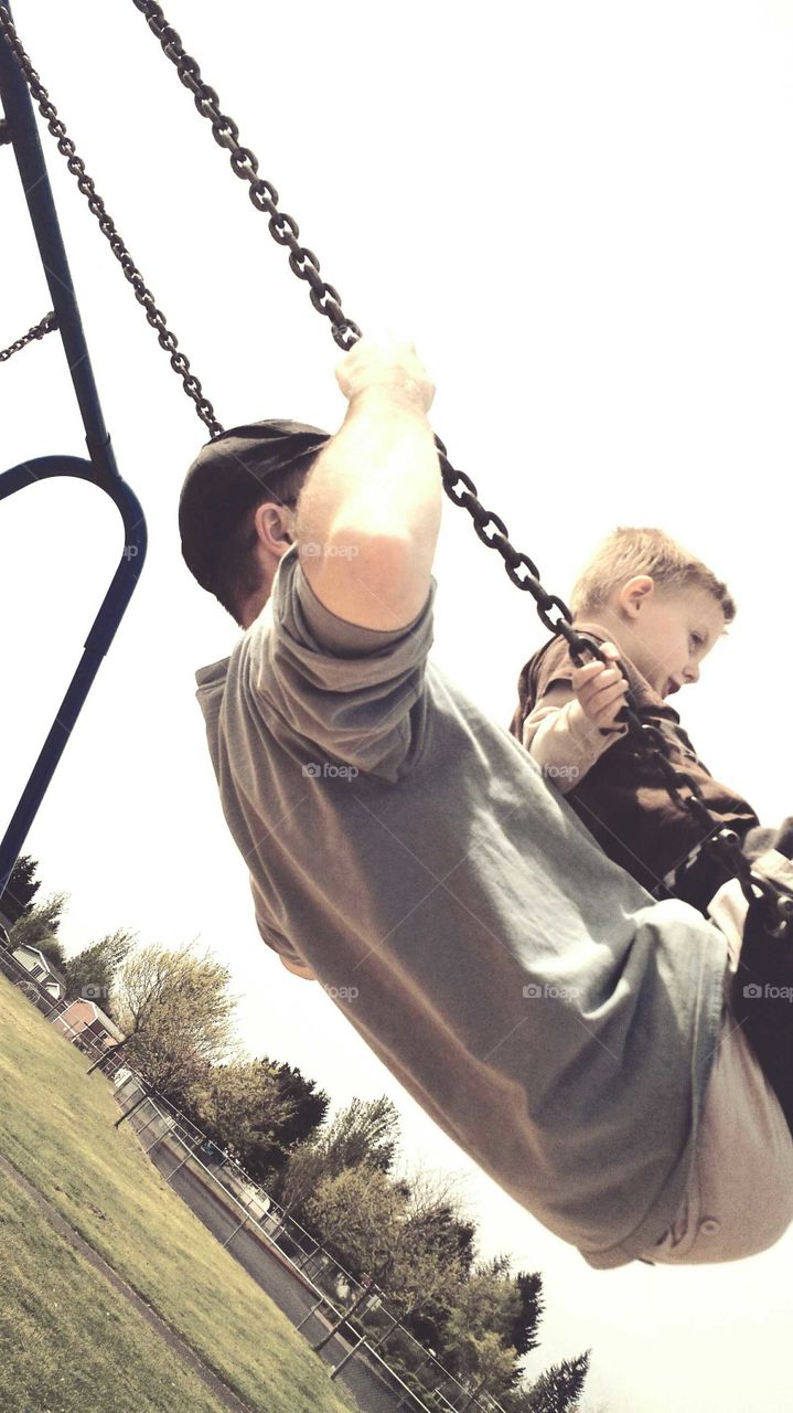 father and son playing on swing