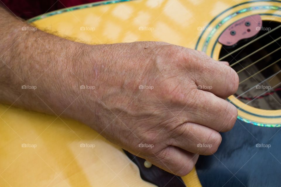 Older man strumming his guitar.
