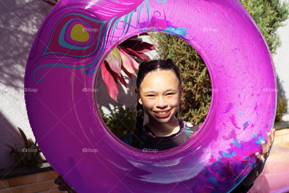 Child having fun in the pool with magenta color float.