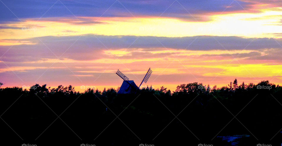 Silhouetted windmill against the sunset sky taken from a cruise ship whilst passing through the Stockholm archipelago