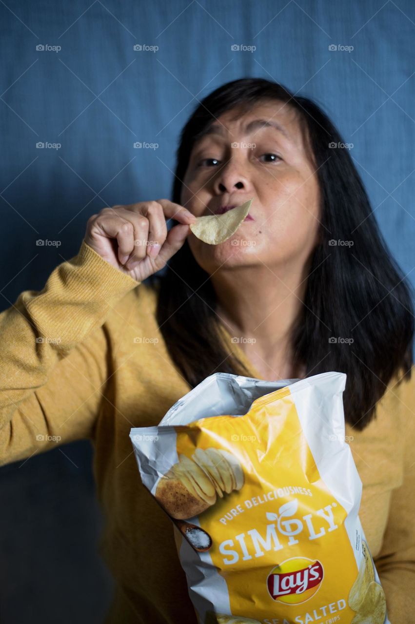 Portrait of a woman eating potato chips 