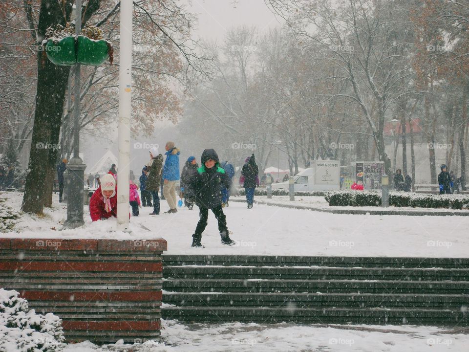 children playing snowballs in a winter park