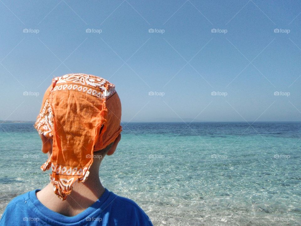 summertime, boy with orange bandana gazing the sea