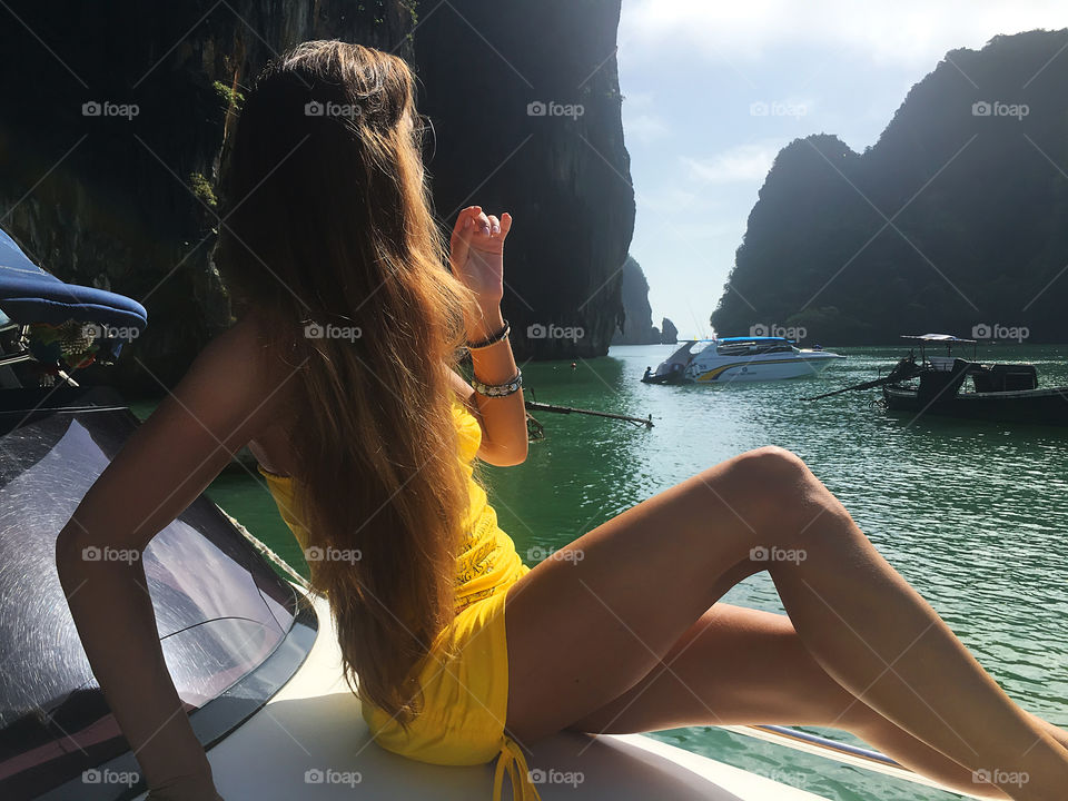 Young woman in yellow dress traveling by boat in sea 