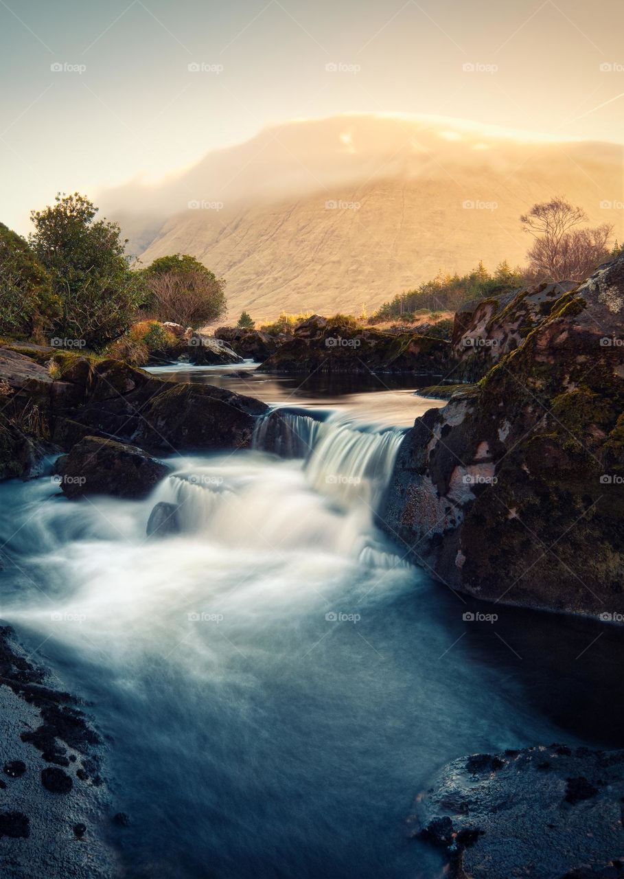 Morning sunrise landscape scenery with small waterfall on river Erriff with mountains in the background at Aesleagh in county Mayo, Ireland