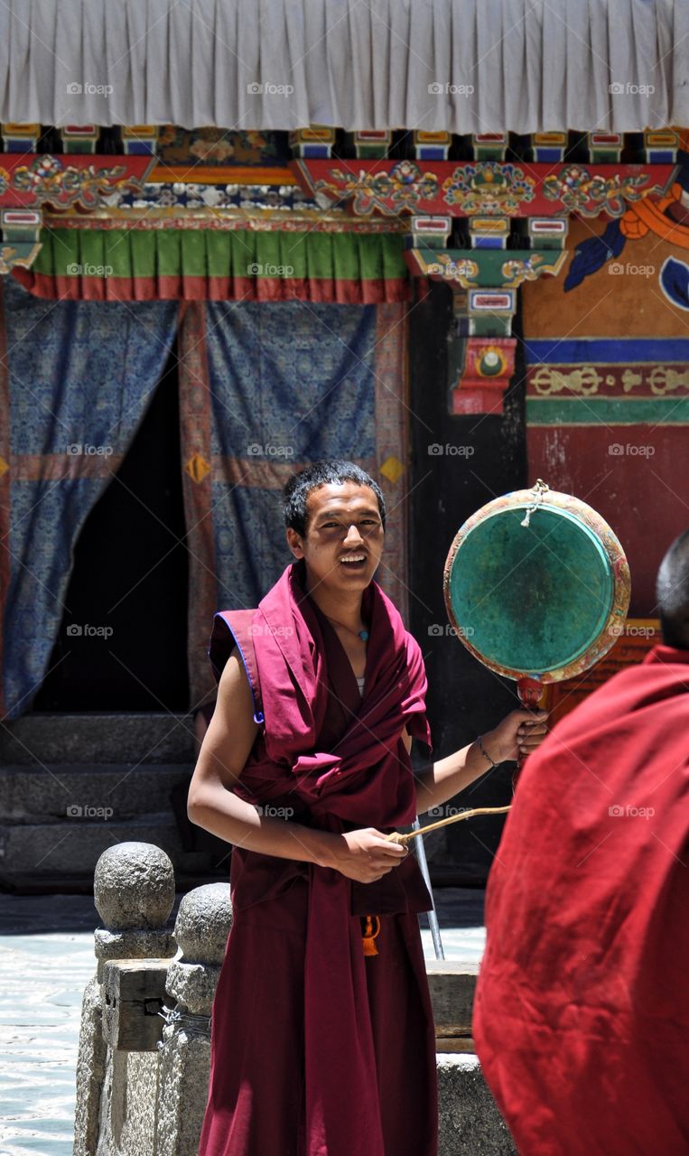 buddhist monk in sakya monastery playing musical instruments in the yard of the temple