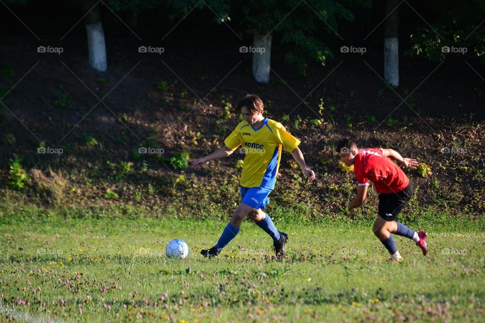 The player of the yellow team took the ball and leads forward.