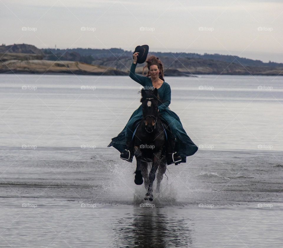 Woman ,riding her horse at the beach . She play and having fun at the beach and flirt with the photographer.