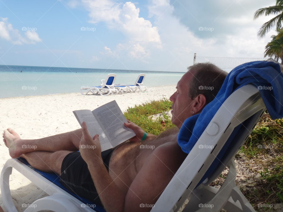 Man reading lying on the beach