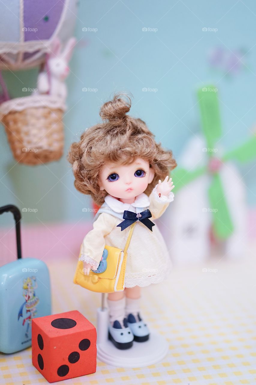 Cute BJD doll. BJD stands for Ball-Jointed-doll. A doll dress up in lovely yellow dress and curled hair. The little girl is ready to go to school