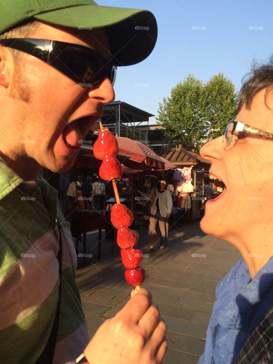 Enjoying candied strawberries on a stick 
